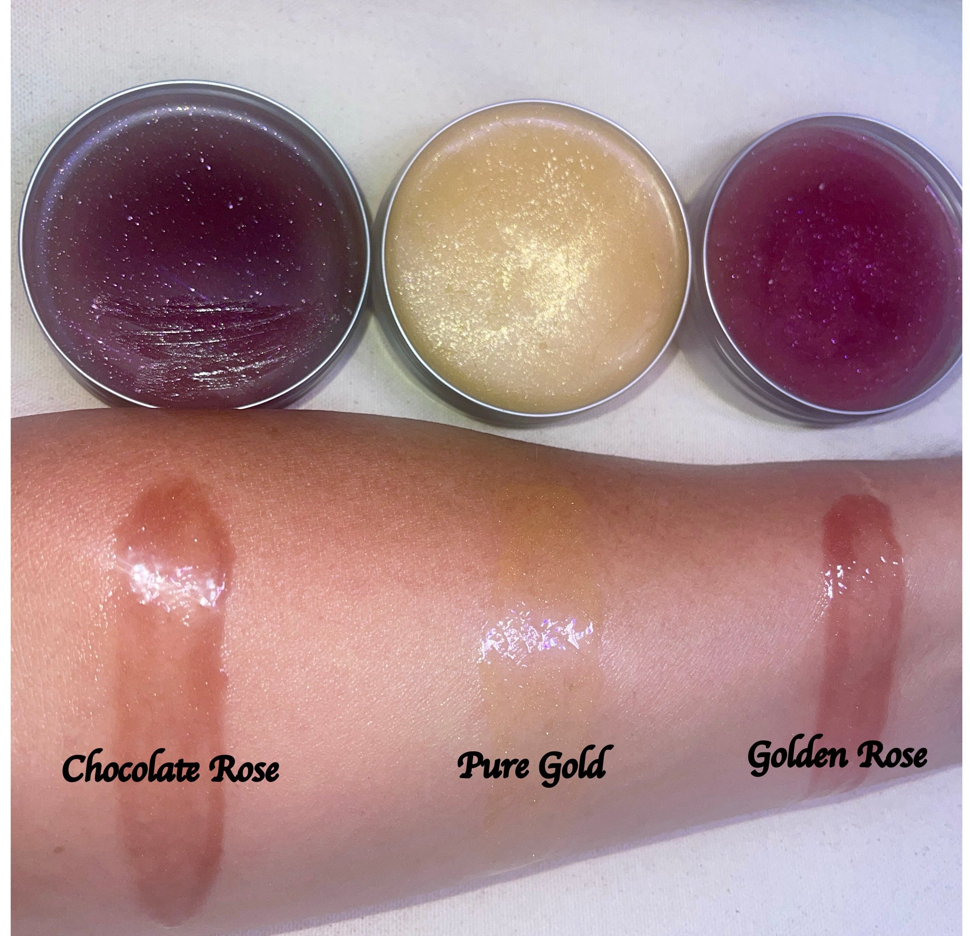 Three face balm tins with swatches on a person's arm labeled 'Chocolate Rose', 'Pure Gold', and 'Golden Rose'.